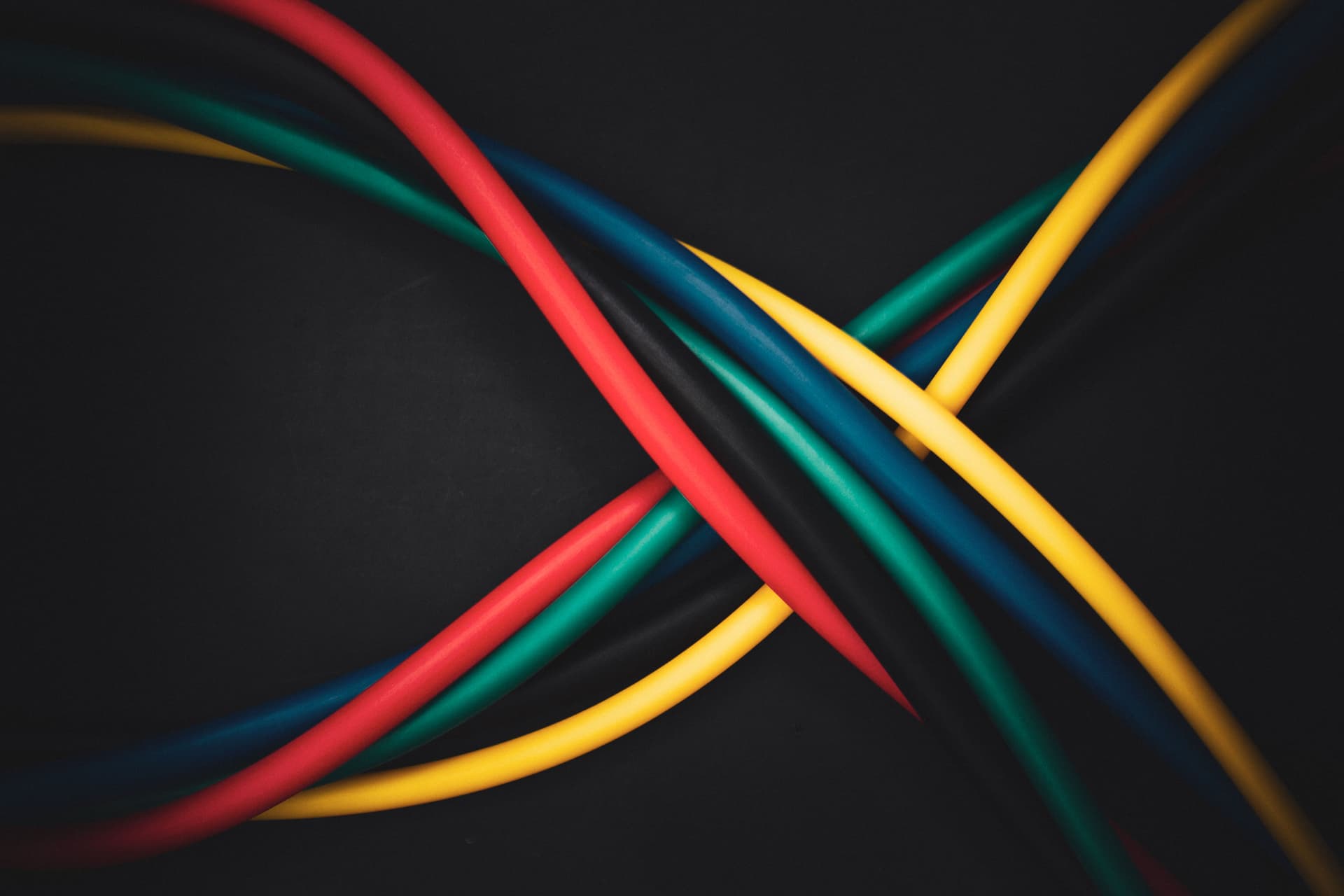 Multi-colored cables crossing over one another against a dark background.
